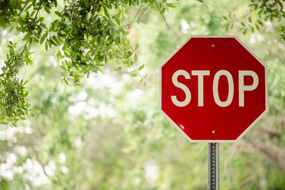 Znak stop obok pomidora, sugerujący ograniczenie spożycia tego warzywa w okresie karmienia piersią, aby uniknąć reakcji alergicznych.